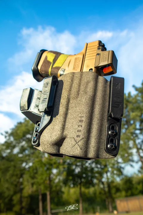 Tan handgun in a textured holster photographed outdoors